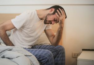 Young man in sleepwear suffering from headache in morning