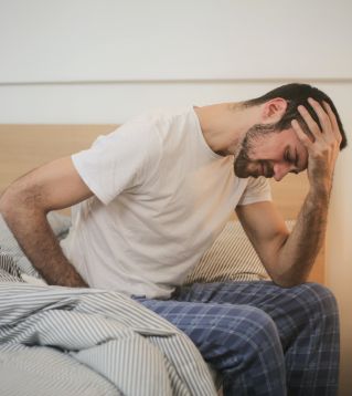 Young man in sleepwear suffering from headache in morning